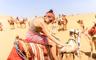 Camel ride experience at Giza Complex with tourists in the background.