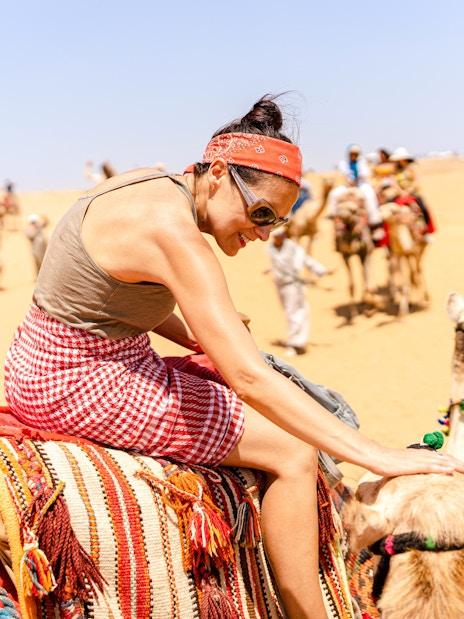 Camel ride experience at Giza Complex with tourists in the background.