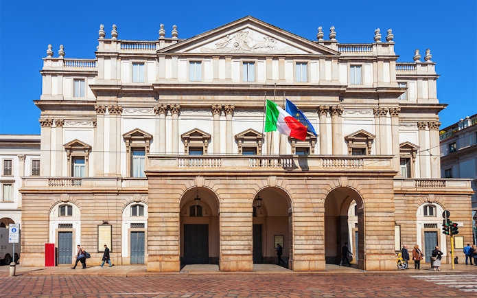 La Scala Opera House in Milan with Italian and EU flags.