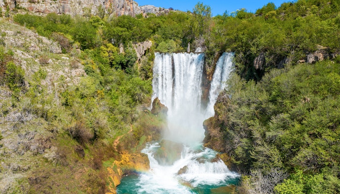 Aerial view of Manojlovac waterfall cascading through lush greenery in Krka National Park, Croatia.