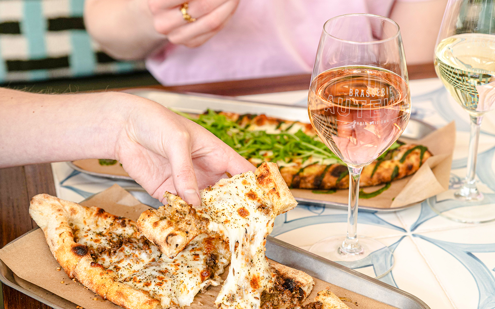 Pizza being shared at Brasserie Auteuil with glasses of wine.