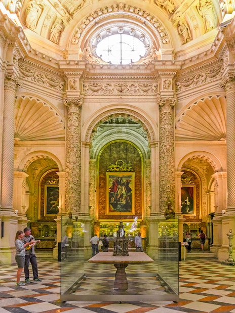 Royal chapel interior with ornate columns and religious paintings, Seville Cathedral, Spain.