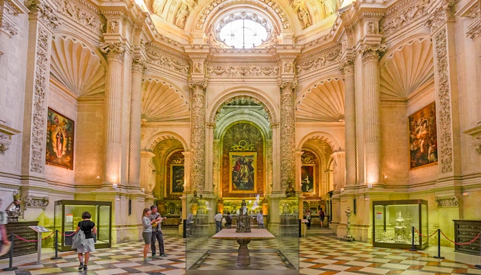 Royal chapel interior with ornate columns and religious paintings, Seville Cathedral, Spain.