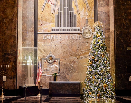 Empire State Building interior with Christmas decorations and festive lights.
