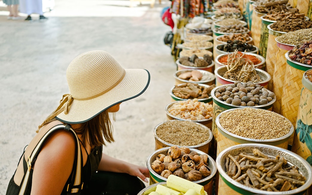 Young woman browsing spice stalls at a traditional market in Dubai.