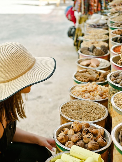 Young woman browsing spice stalls at a traditional market in Dubai.