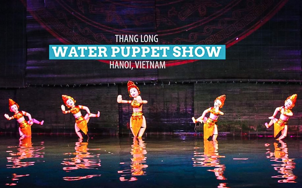 Five puppets in golden costumes performing at Thang Long Water Puppet Show, Hanoi.