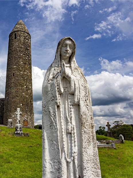 Glendalough Monastic Site with round tower and statue in a historic cemetery.