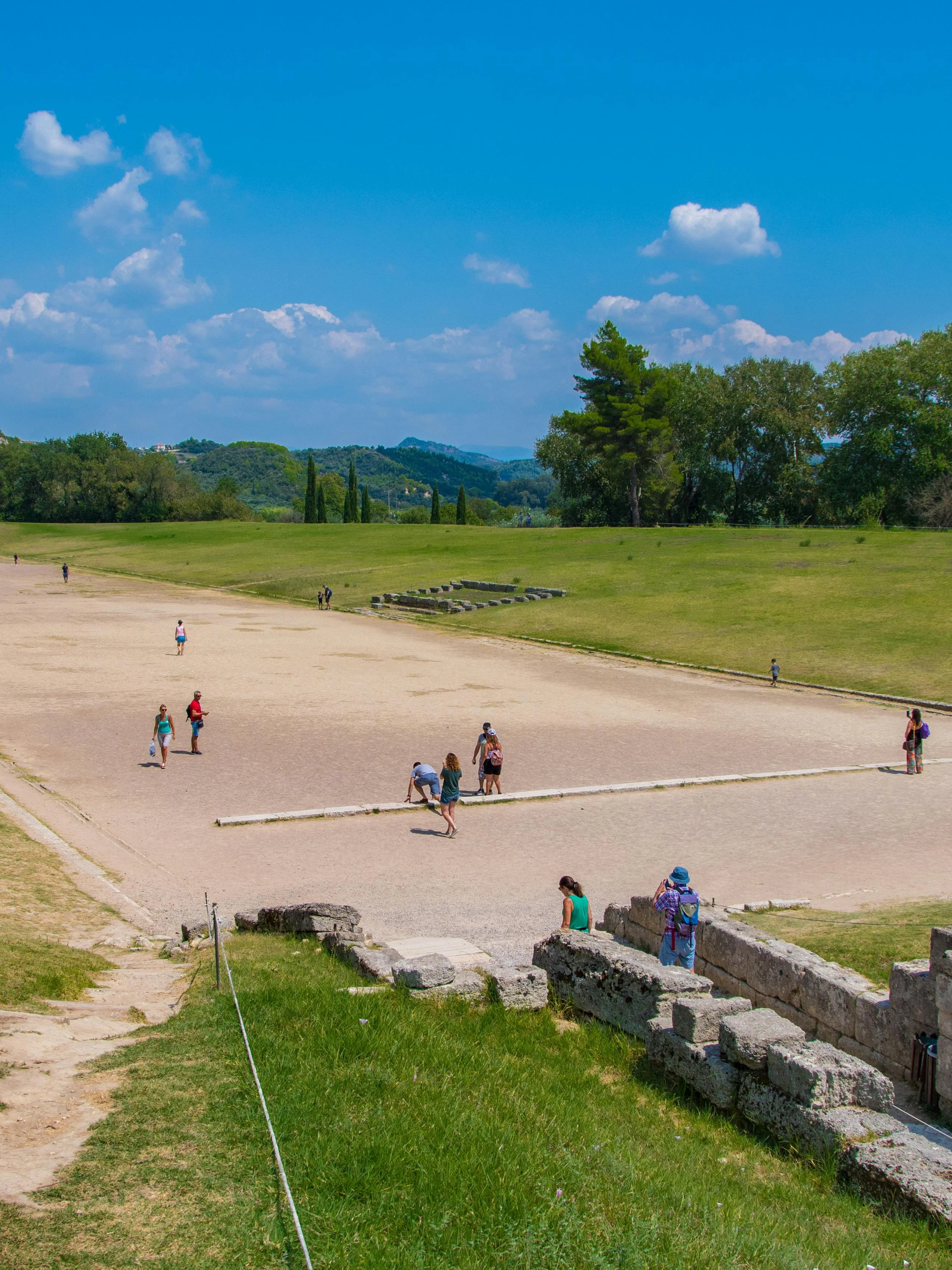 Stadium at the Archaeological Site of Olympia, Greece, with visitors exploring the ancient track.