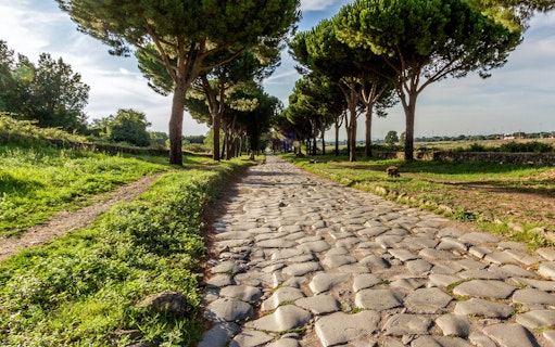 Ancient cobblestone road lined with trees on the Catacombs Tour in Rome, Italy.