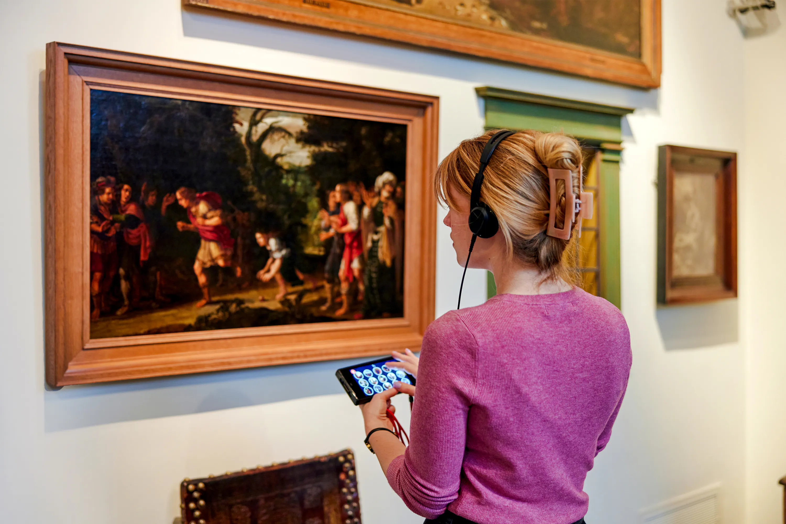 Visitor with audio guide viewing painting at Rembrandt House Museum, Amsterdam.