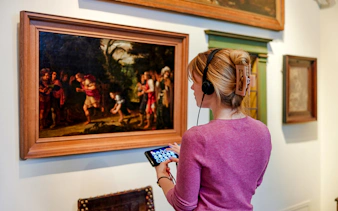 Visitor with audio guide viewing painting at Rembrandt House Museum, Amsterdam.