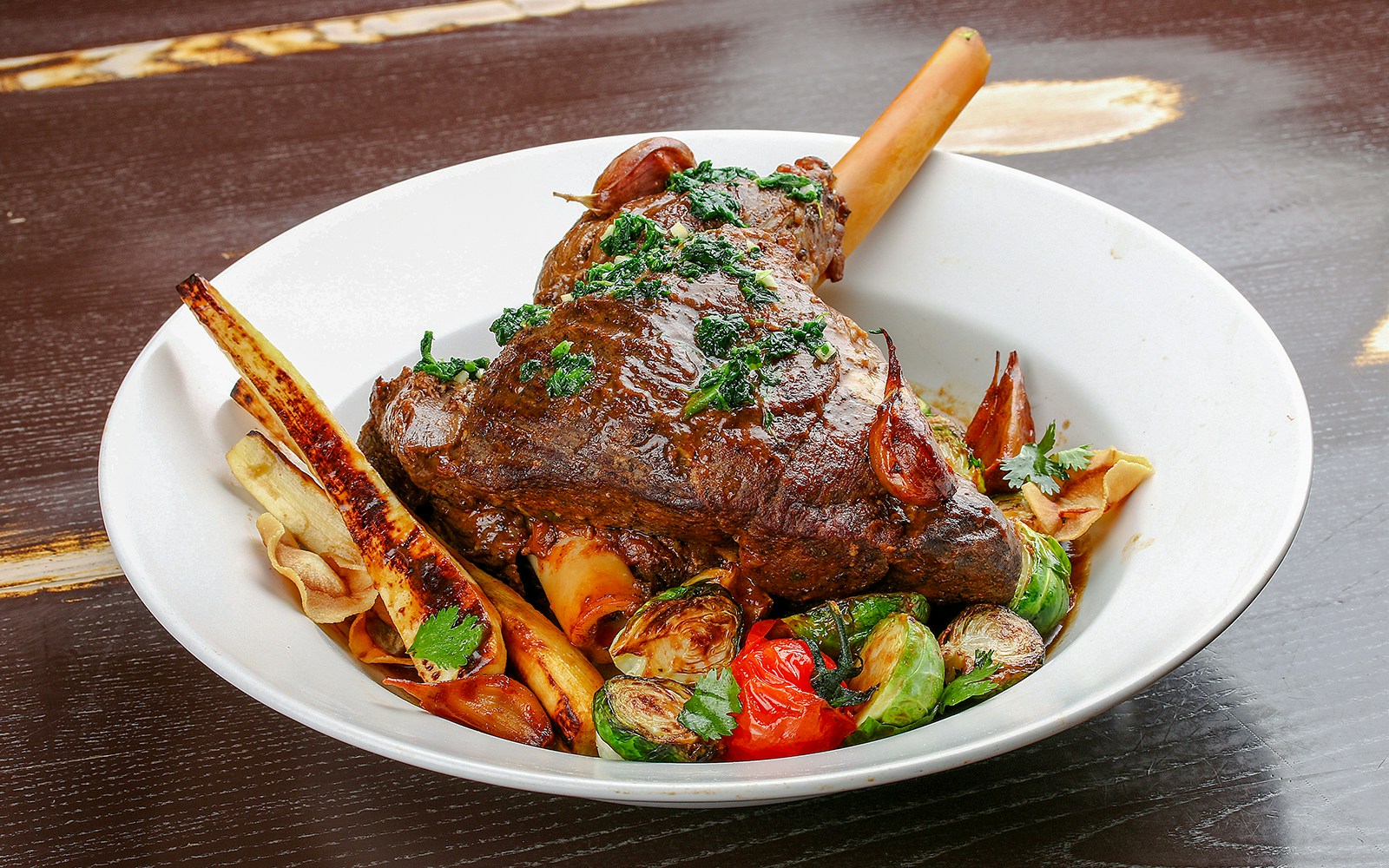 Roast lamb dish served at Orbit Revolving Restaurant, Kuala Lumpur, with city skyline view.