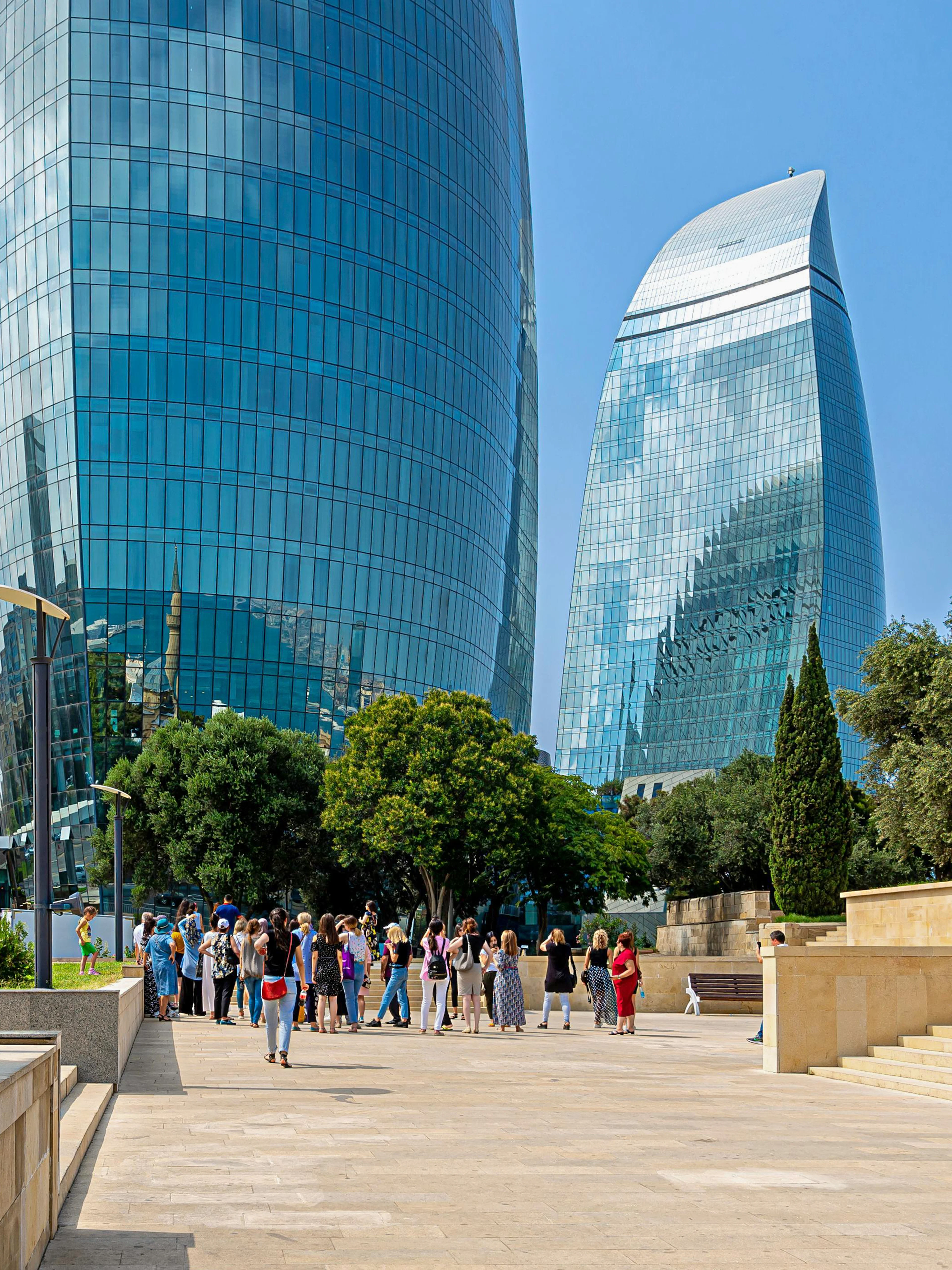 Flame Towers complex in Baku with nearby mosque and tourists exploring.