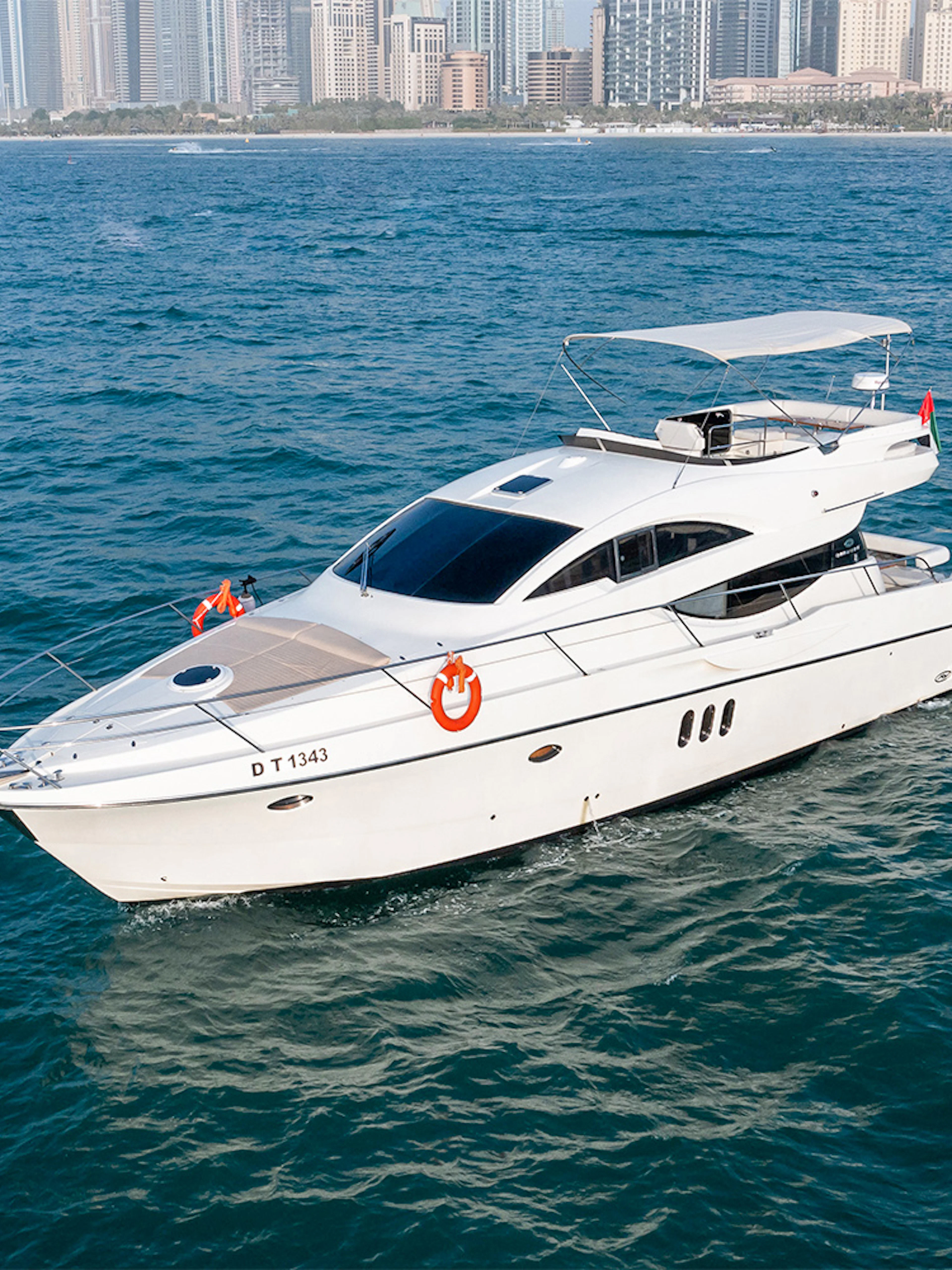 Private yacht Veronika 55 cruising in Dubai with city skyline in background.