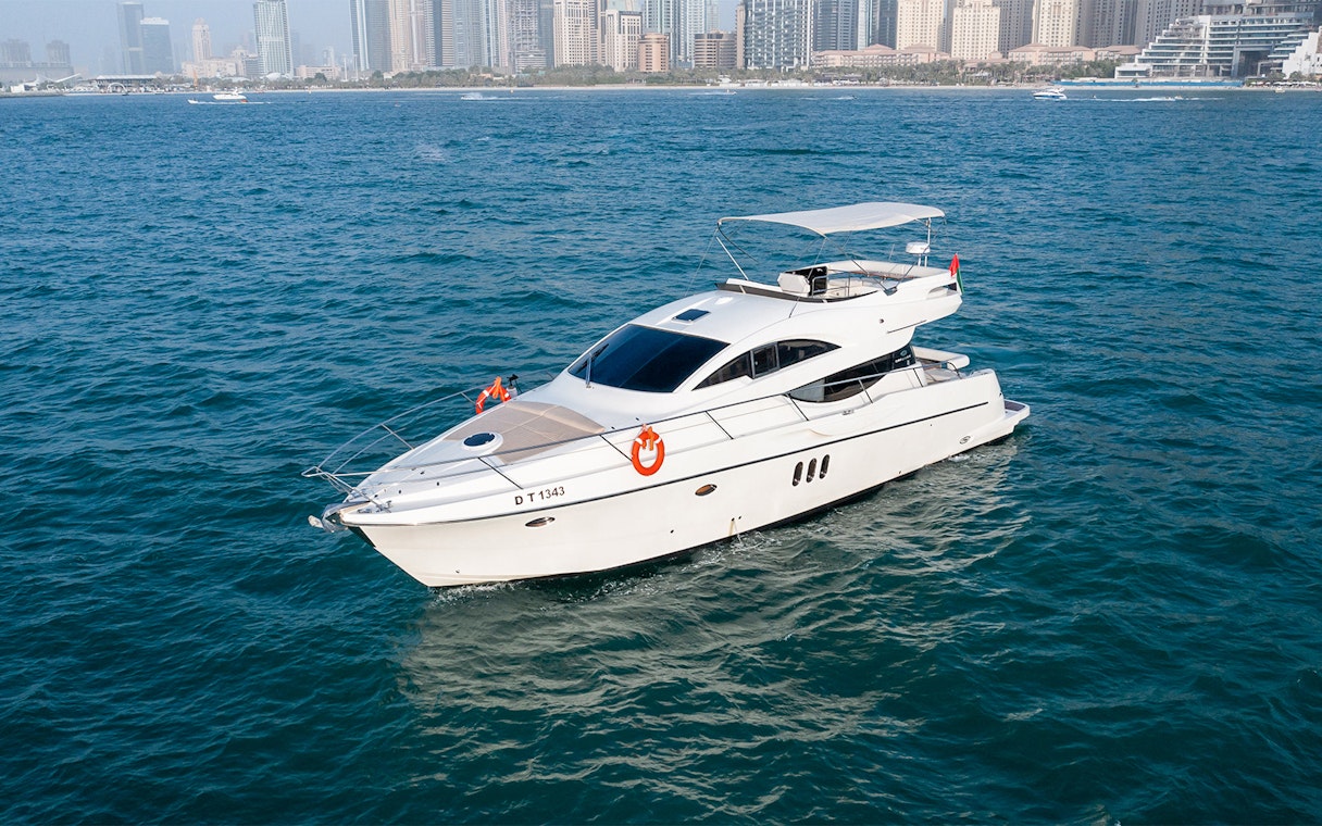 Private yacht Veronika 55 cruising in Dubai with city skyline in background.