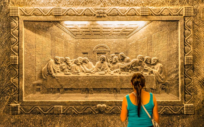 Visitor admiring Last Supper salt carving at Wieliczka Salt Mine, Krakow.