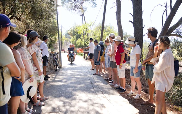 Locals and tourists watch a scooter pass on a path in Kolocep Island, Dubrovnik.