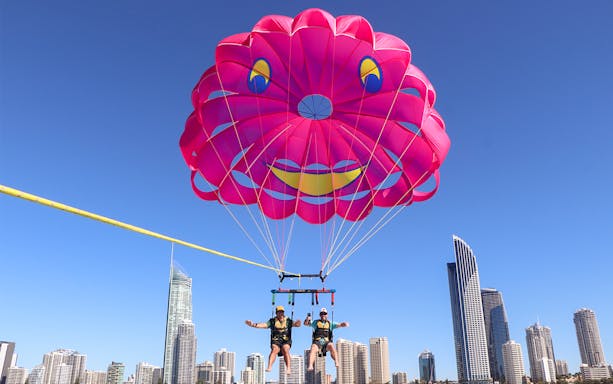 Parasailing over city skyline with pink parachute, Jet Ski, Parasail & Jetboat Experience.