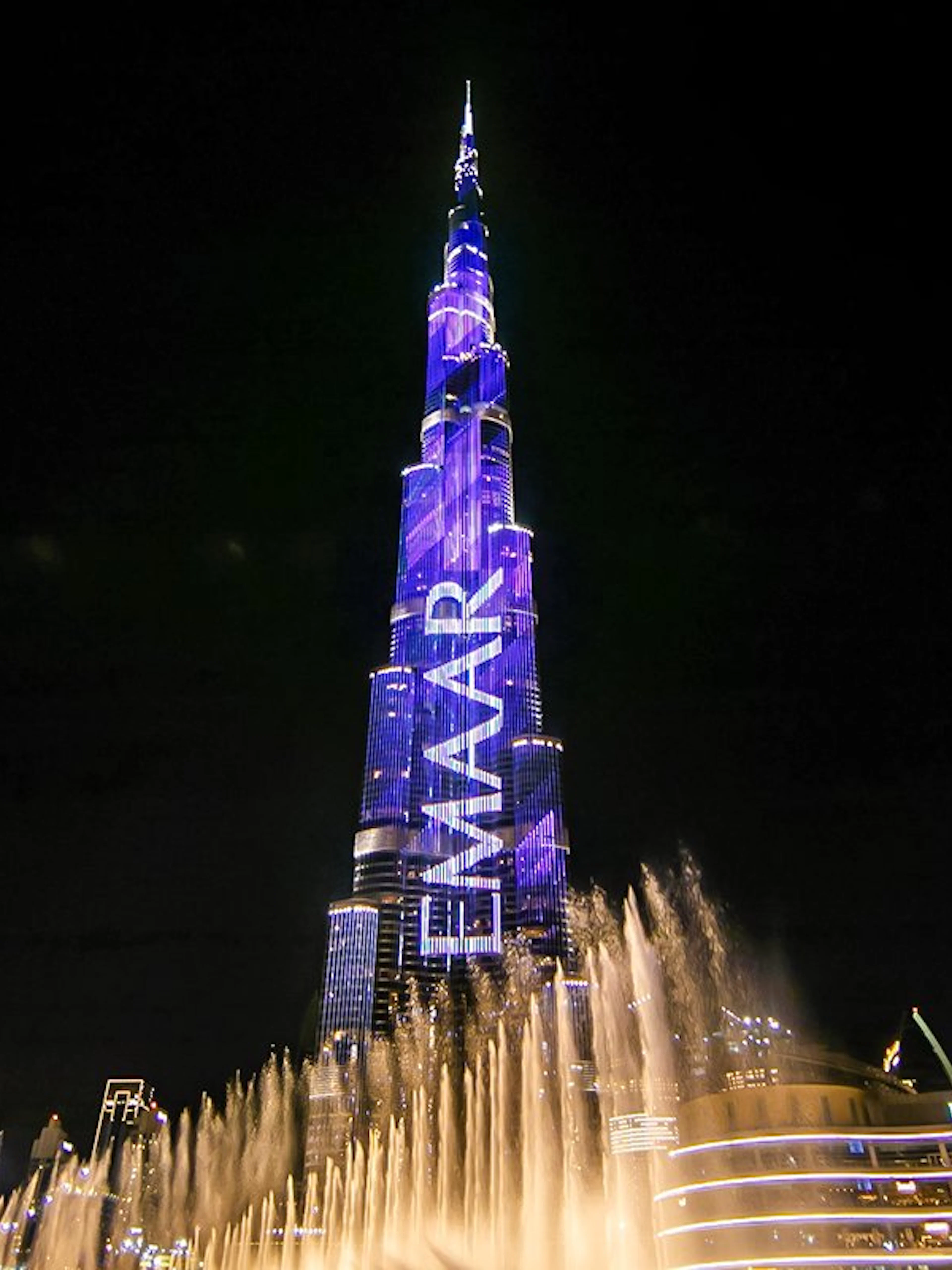 Dubai Fountain show with Burj Khalifa illuminated at night.