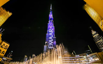 Dubai Fountain show with Burj Khalifa illuminated at night.