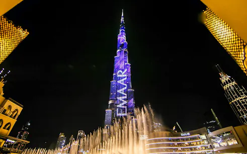 Dubai Fountain show with Burj Khalifa illuminated at night.