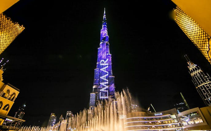 Dubai Fountain show with Burj Khalifa illuminated at night.