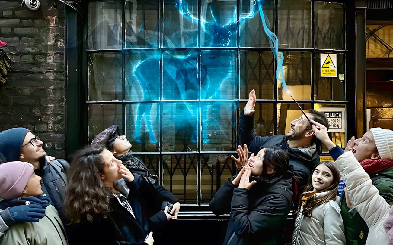 Group on Harry Potter walking tour in York, admiring a glowing stag projection on a window.