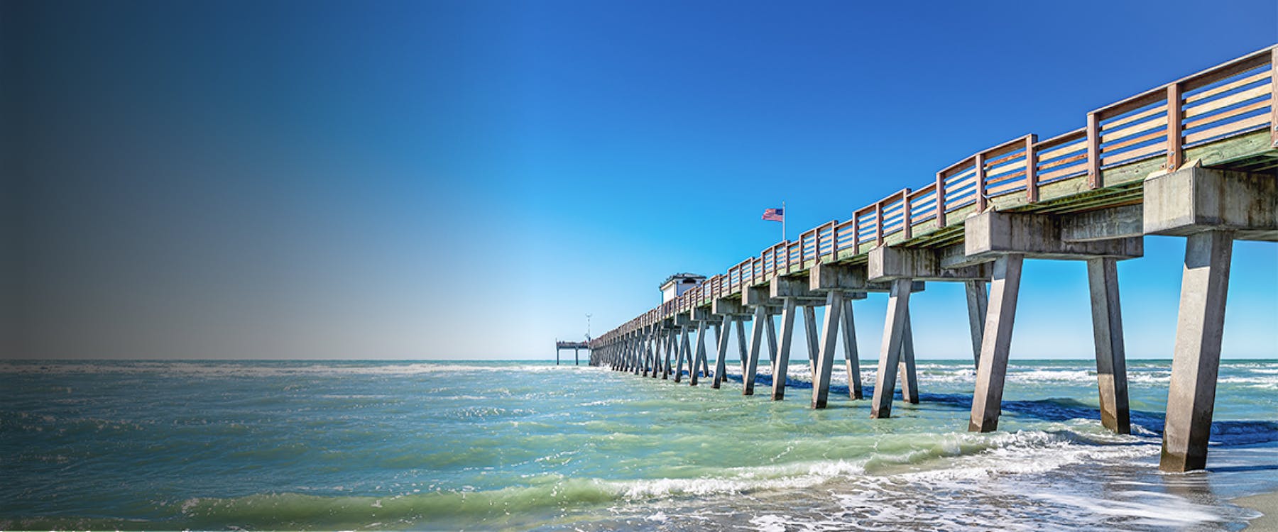 Clearwater Beach pier extending over the ocean under a clear blue sky.