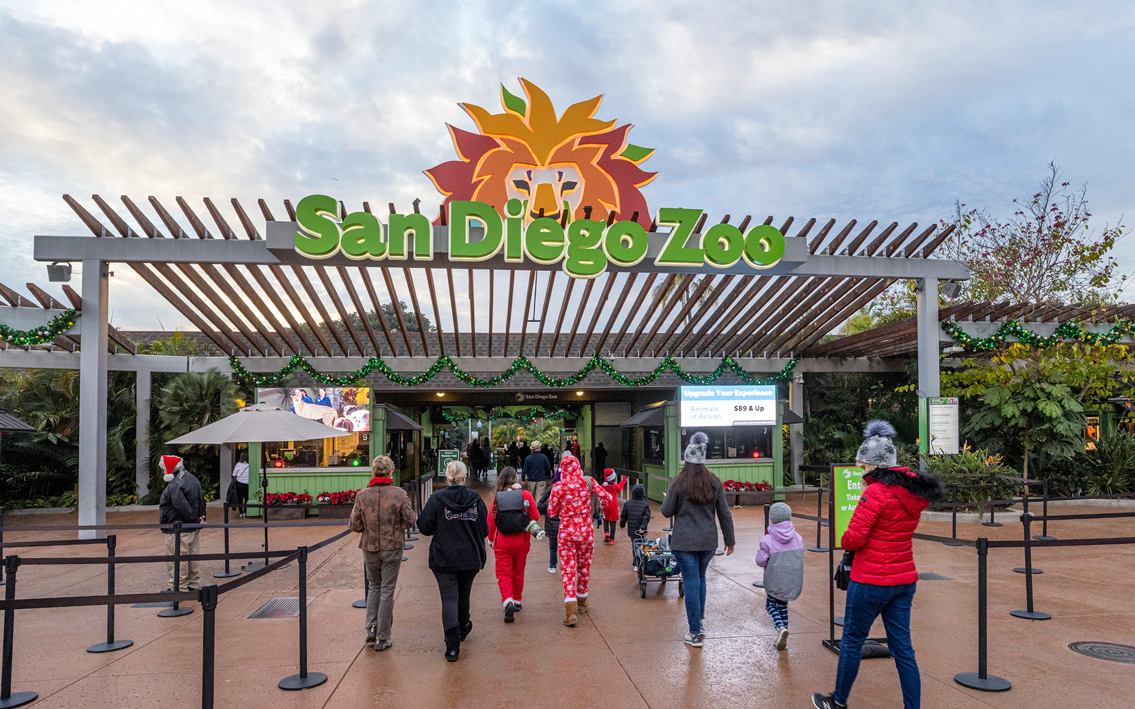 Visitors entering the San Diego Zoo under a decorated entrance sign.
