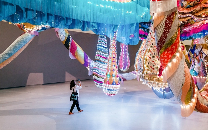 Colorful textile installation at MAAT Gallery with visitor taking a photo.