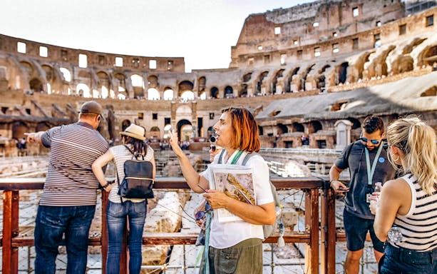 Tour guide explaining Colosseum history to tourists on the Arena Floor in Rome.