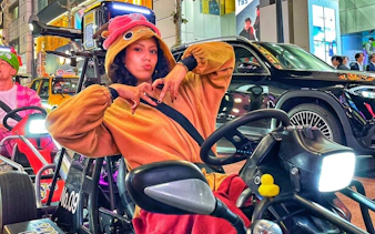 Go-karting tour participant in costume driving through Shibuya, Tokyo at night.