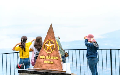 Ba Den mountain summit marker with tourists enjoying the view.