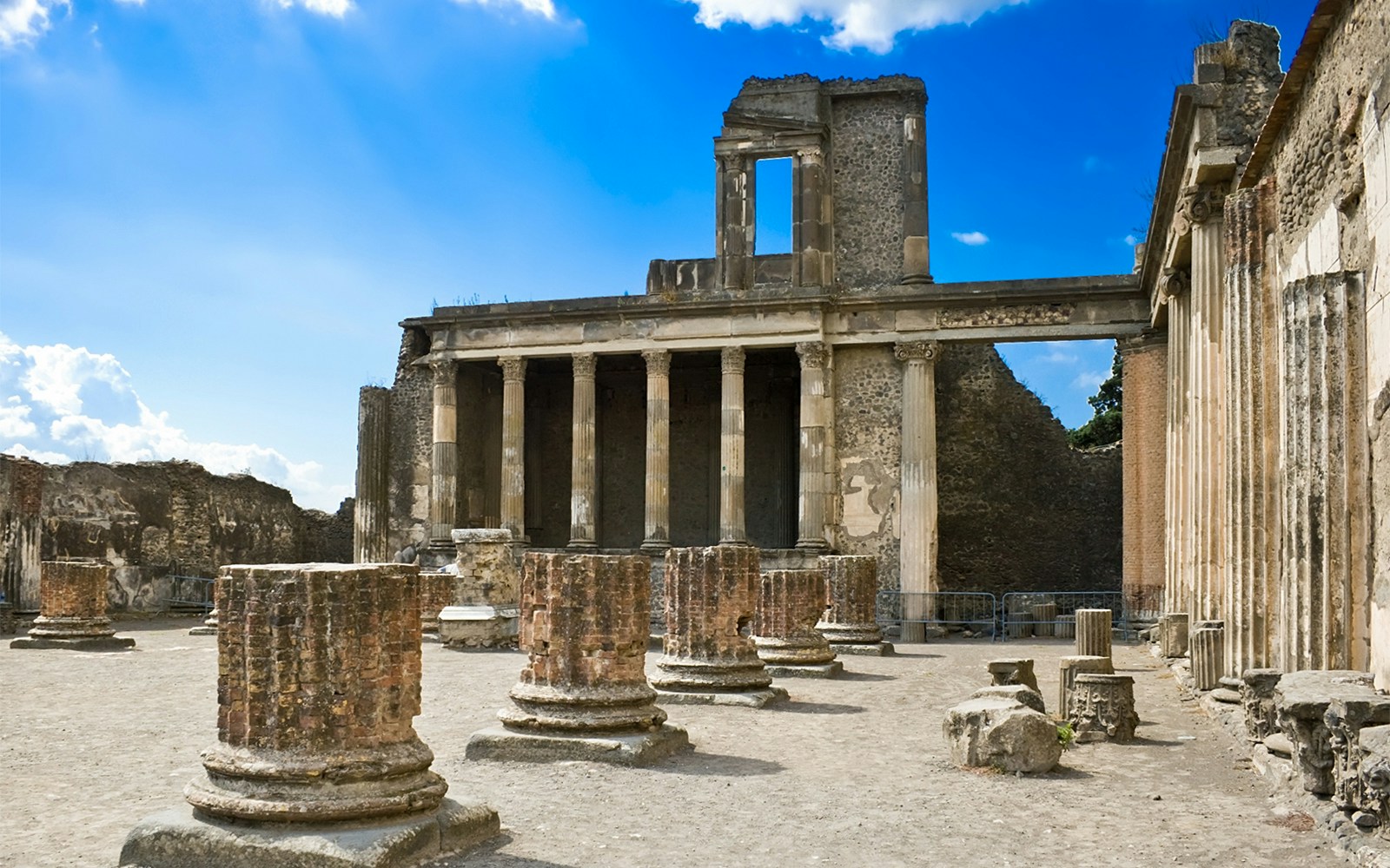 Pompeii Basilica ruins with ancient columns under a clear blue sky.