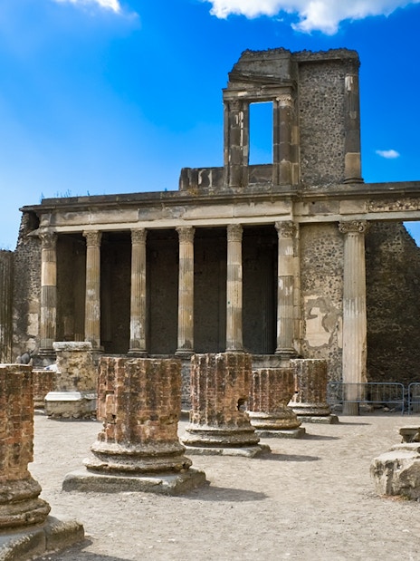 Pompeii Basilica ruins with ancient columns under a clear blue sky.