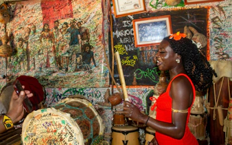 Local artisan playing traditional drums in a vibrant San Basilio de Palenque cultural house.