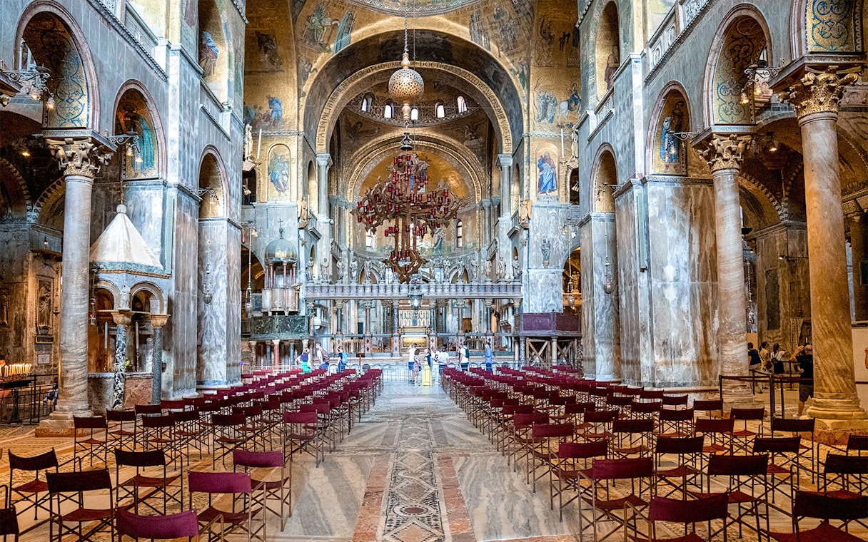 Interior of St. Mark’s Basilica in Venice with ornate arches and empty seating.