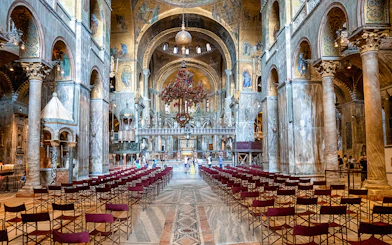 Interior of St. Mark’s Basilica in Venice with ornate arches and empty seating.