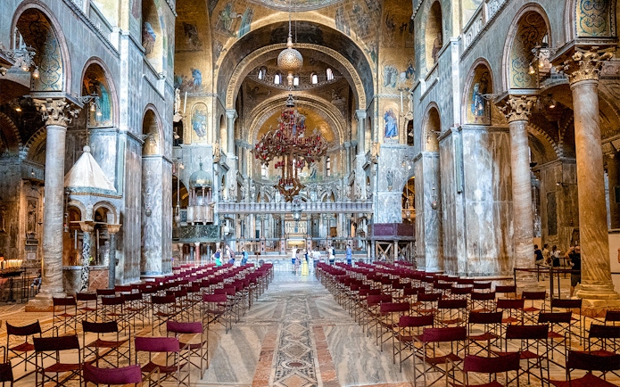 Interior of St. Mark’s Basilica in Venice with ornate arches and empty seating.