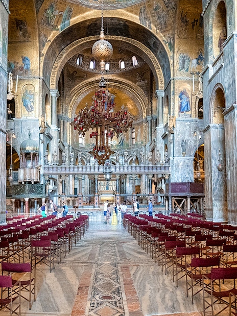 Interior of St. Mark’s Basilica in Venice with ornate arches and empty seating.