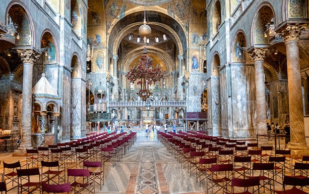 Interior of St. Mark’s Basilica in Venice with ornate arches and empty seating.