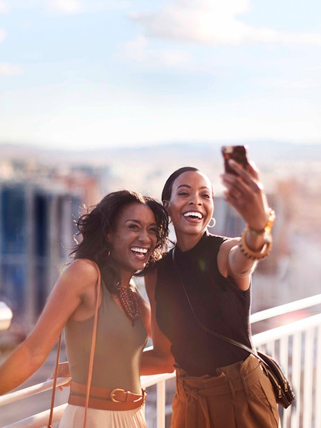 Two people taking a selfie on a Las Vegas observation deck with city view.