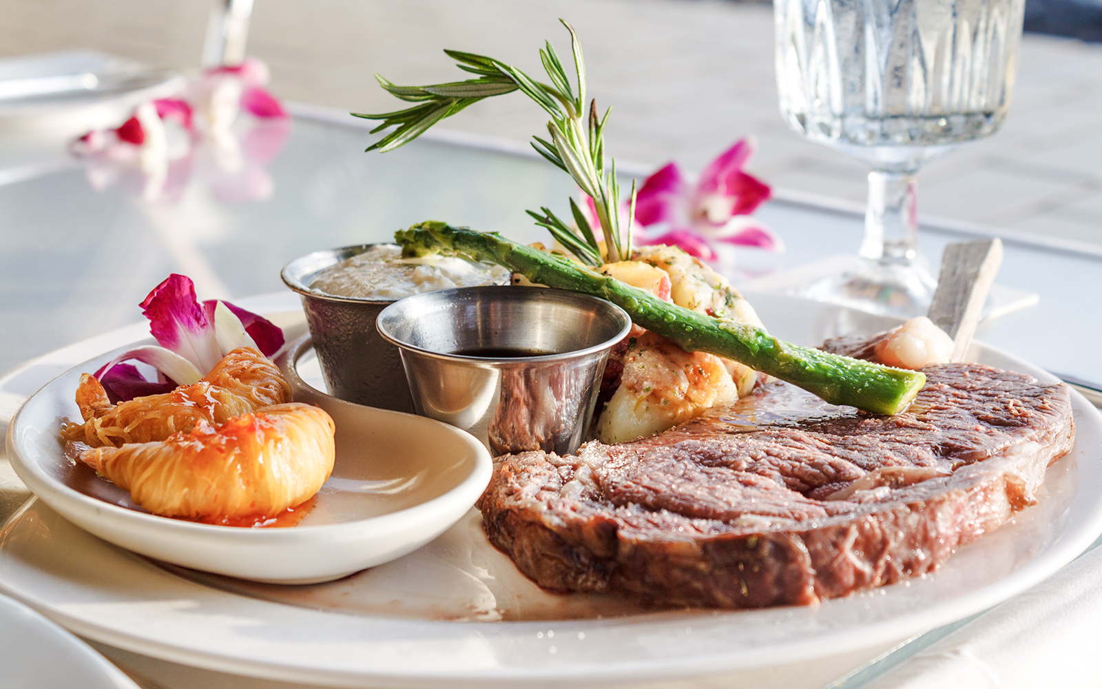Prime rib with asparagus and tropical garnish on a plate.