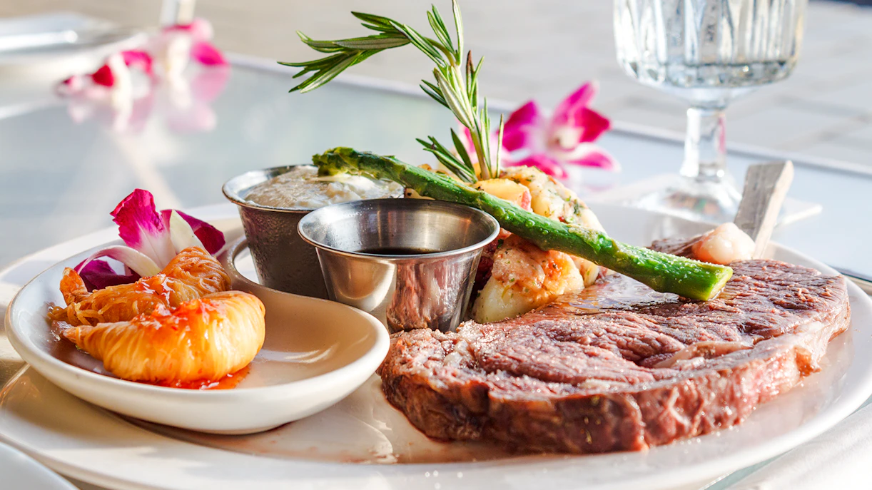 Prime rib with asparagus and tropical garnish on a plate.