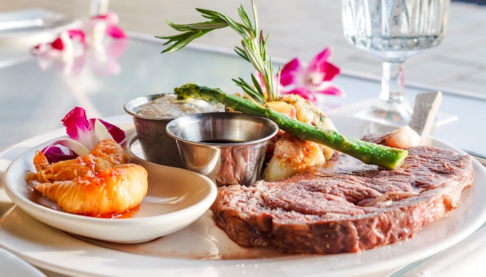 Prime rib with asparagus and tropical garnish on a plate.
