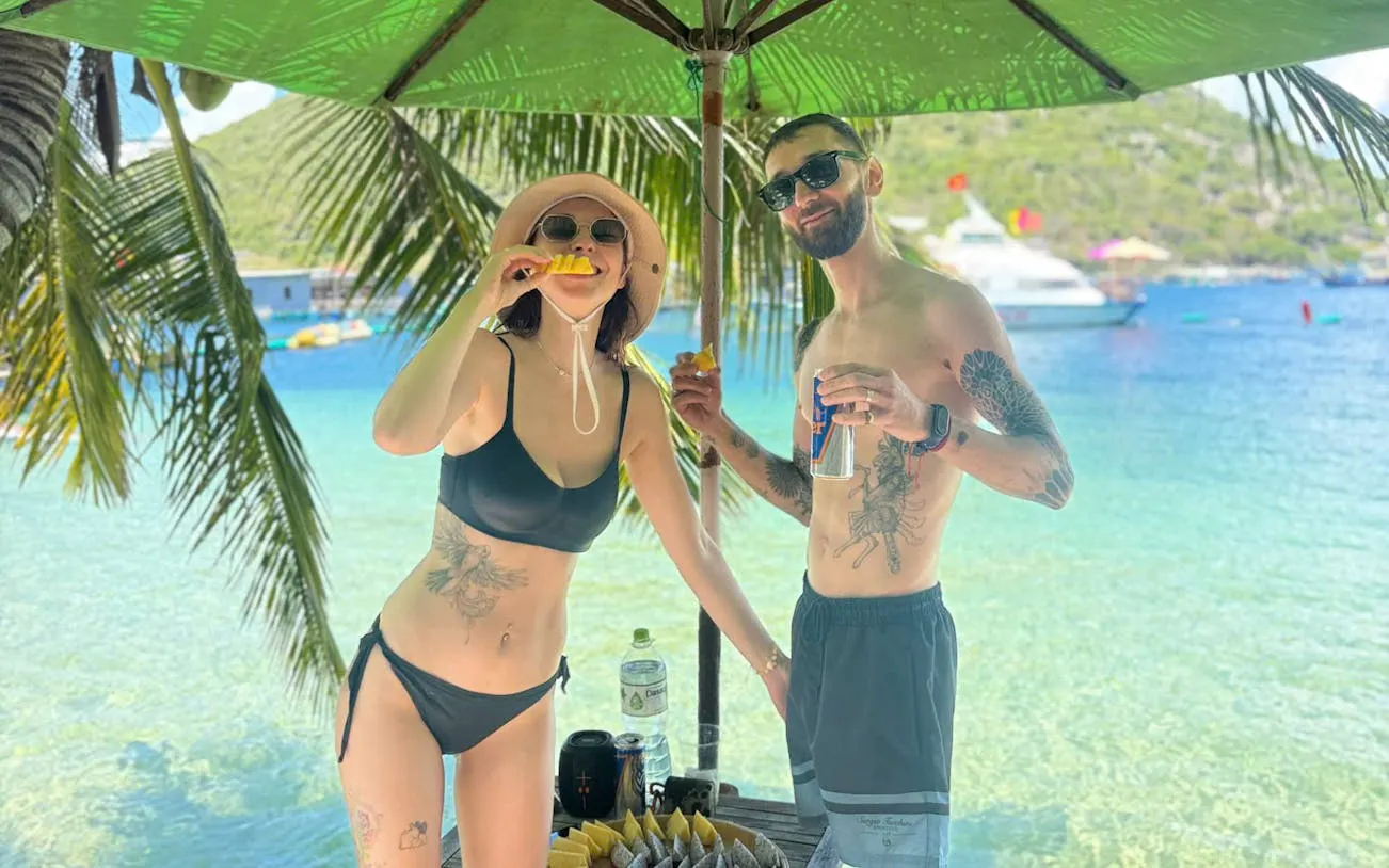 Couple enjoying tropical fruit on Robinson Beach, Nha Trang island-hopping tour.