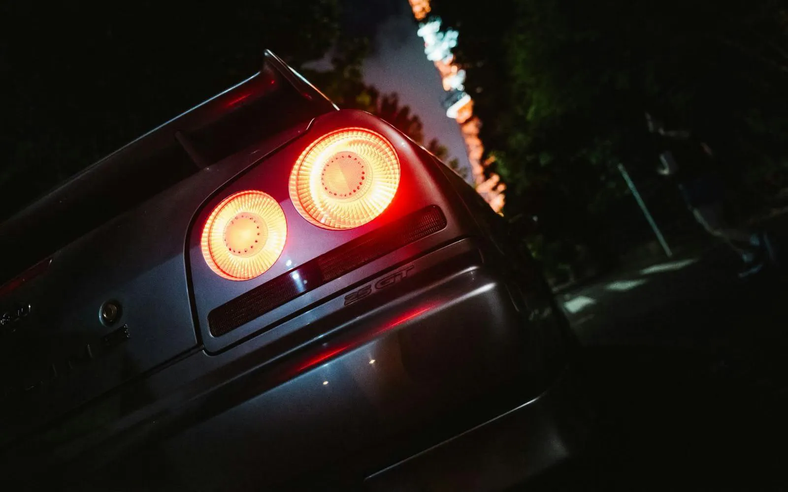 Rear view of a sports car with glowing taillights in Tokyo at night.