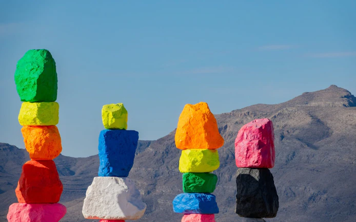Colorful rock formations at Seven Magic Mountains near Las Vegas with desert mountains in the background.