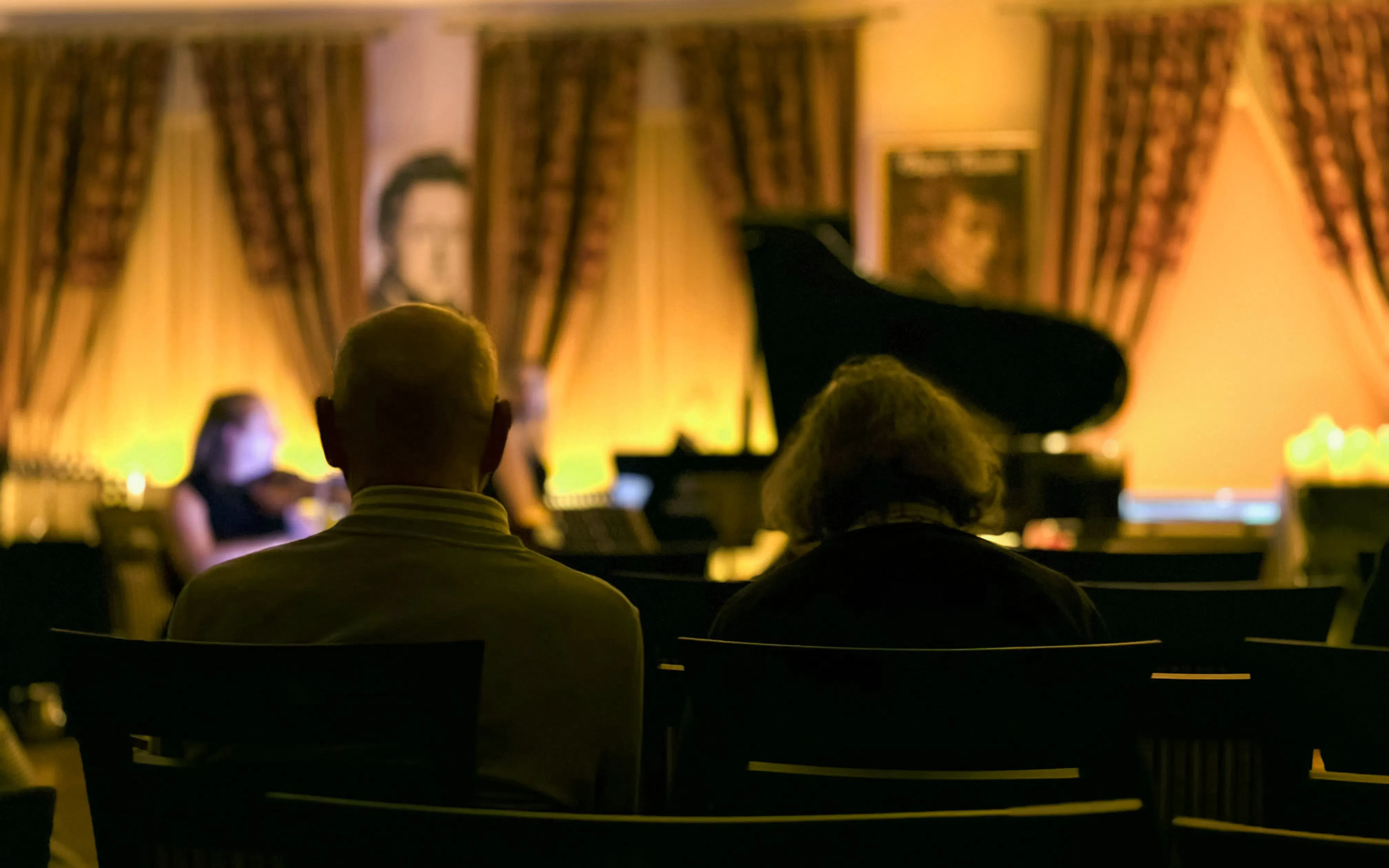 Audience at candlelit Queen music performance, Chopin Gallery, Krakow.
